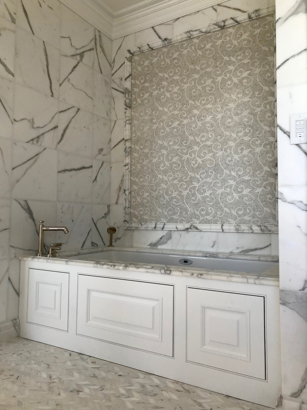 Calacatta marble tub surround with decorative mosaic accent